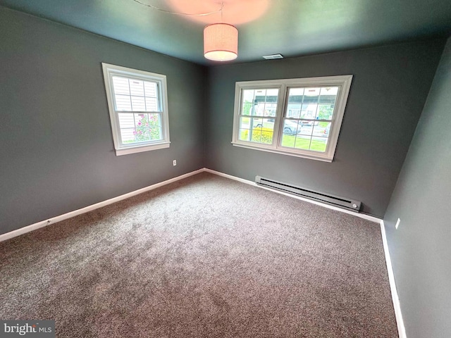 carpeted spare room featuring baseboard heating, healthy amount of natural light, and baseboards