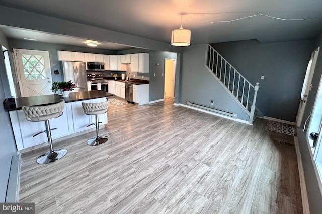 kitchen featuring appliances with stainless steel finishes, a baseboard heating unit, dark countertops, and light wood-style floors