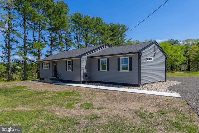 ranch-style house featuring roof with shingles, entry steps, and a front yard