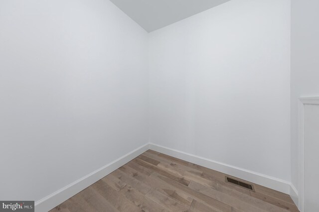 unfurnished room featuring baseboards, lofted ceiling, light wood finished floors, and visible vents