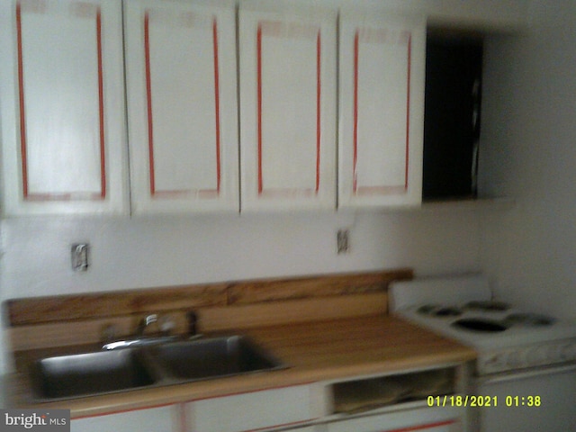 kitchen with white stove, a sink, and light countertops