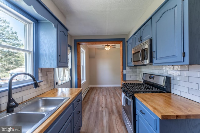 475 Farmington Ave, Pottstown, PA 19464 - kitchen featuring stainless steel appliances, a sink, butcher block countertops, blue cabinetry, and light wood-style floors
