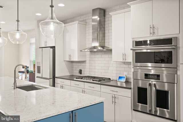 20790 Duxbury Ter, Ashburn, VA 20147 - kitchen with stainless steel appliances, wall chimney range hood, white cabinetry, recessed lighting, and tasteful backsplash
