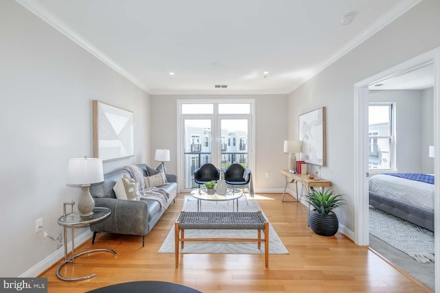living area with baseboards, ornamental molding, light wood-style flooring, and visible vents