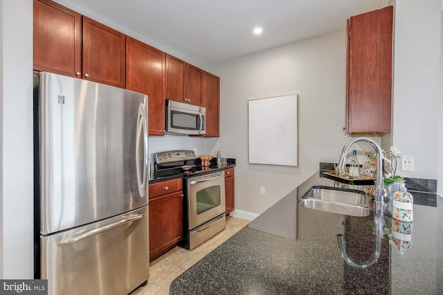 kitchen with light tile patterned flooring, a sink, dark stone countertops, stainless steel appliances, and recessed lighting