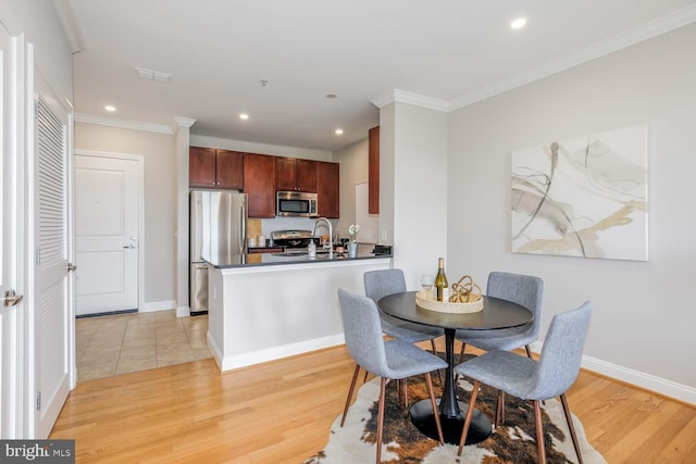 dining space with crown molding, recessed lighting, and light wood-style flooring