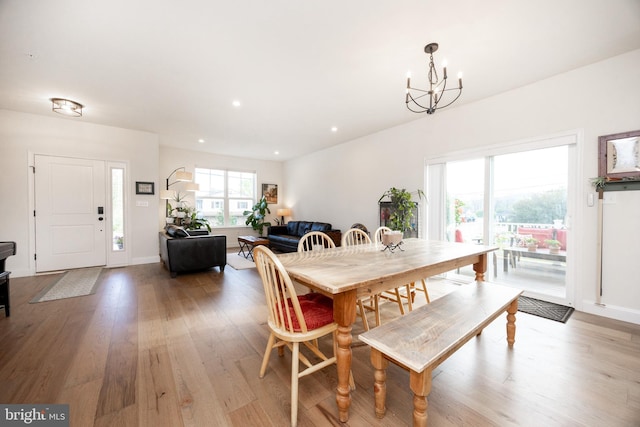 dining space featuring baseboards, recessed lighting, light wood-style flooring, and a notable chandelier