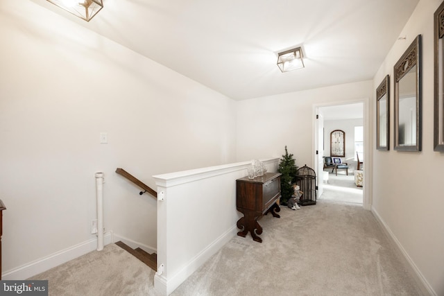 corridor featuring carpet floors, baseboards, and an upstairs landing