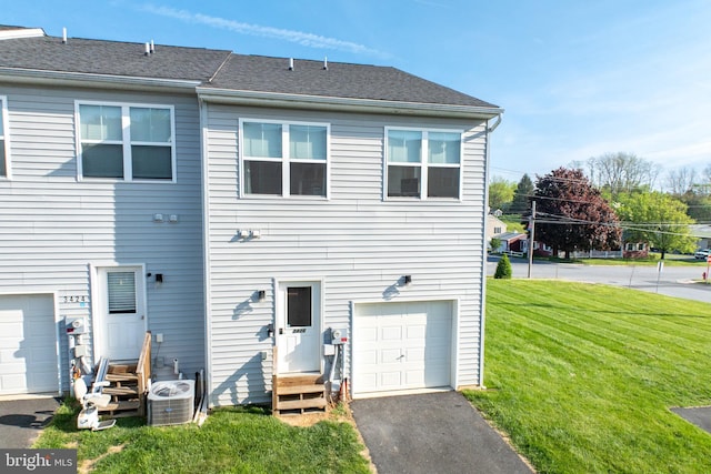 rear view of house featuring driveway, central AC, a yard, an attached garage, and entry steps
