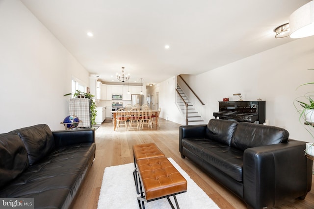 living room with an inviting chandelier, recessed lighting, light wood finished floors, and stairs