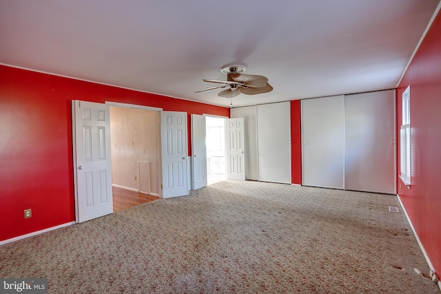 unfurnished bedroom with carpet floors, a ceiling fan, baseboards, and multiple windows