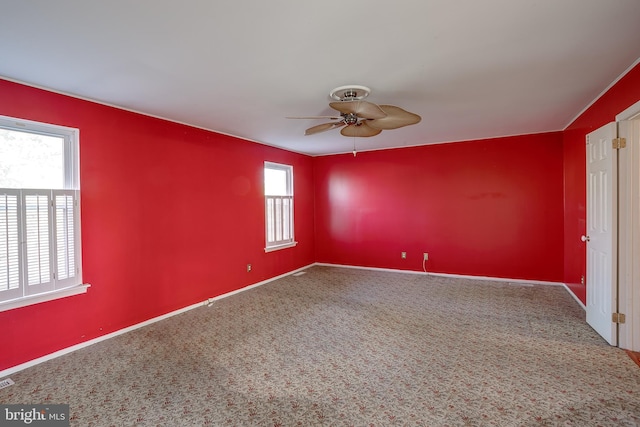 carpeted spare room featuring baseboards and a ceiling fan