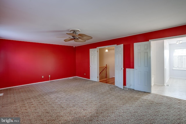carpeted empty room with ceiling fan and baseboards