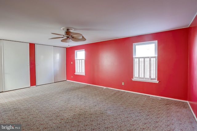 unfurnished bedroom featuring carpet floors, baseboards, visible vents, and ceiling fan