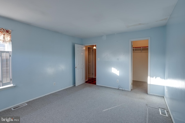 unfurnished bedroom featuring a spacious closet, carpet, and visible vents