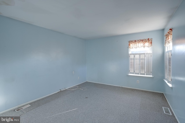 carpeted spare room with visible vents and baseboards