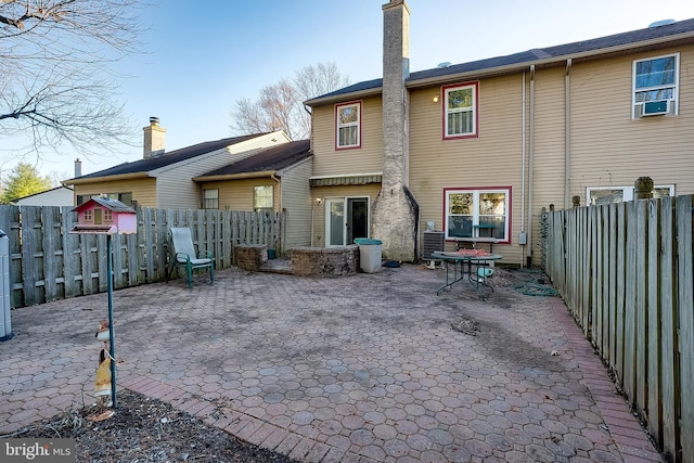 back of property with a fenced backyard, a patio area, and a chimney
