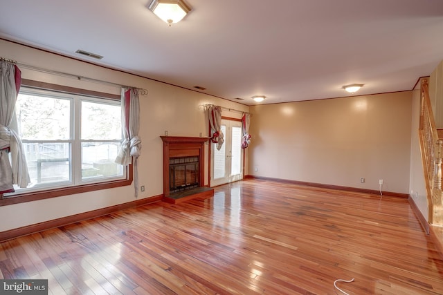 unfurnished living room with light wood-type flooring, baseboards, visible vents, and a fireplace