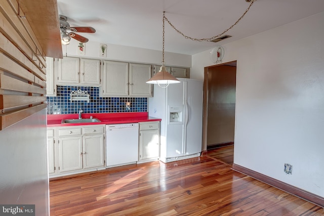 kitchen featuring a ceiling fan, backsplash, a sink, white appliances, and light wood-style flooring