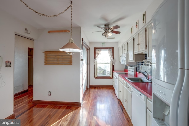kitchen featuring a sink, a ceiling fan, white appliances, and wood finished floors