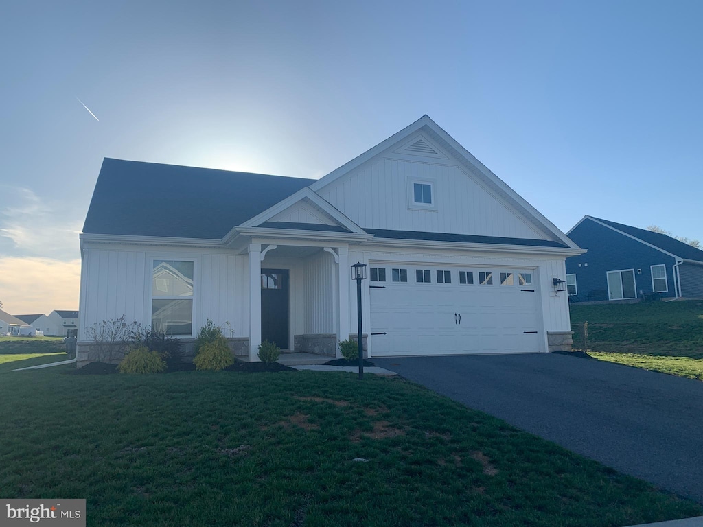 view of front of property with an attached garage, a front lawn, and aphalt driveway