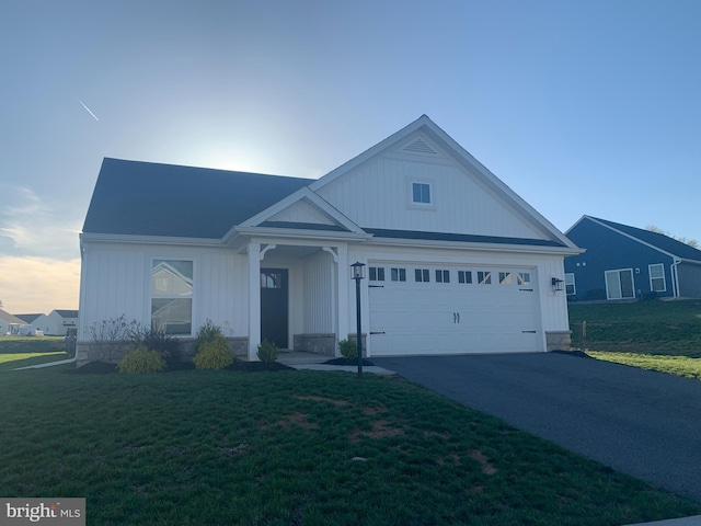 view of front of property with an attached garage, a front lawn, and aphalt driveway