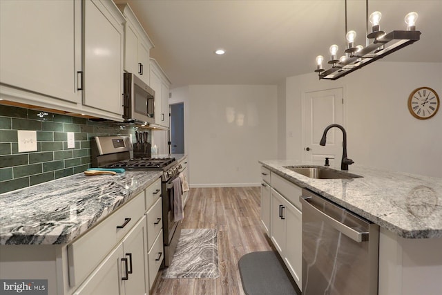 2 Shillington Ln, Carlisle, PA 17013 - kitchen with light stone countertops, appliances with stainless steel finishes, a sink, backsplash, and light wood-type flooring