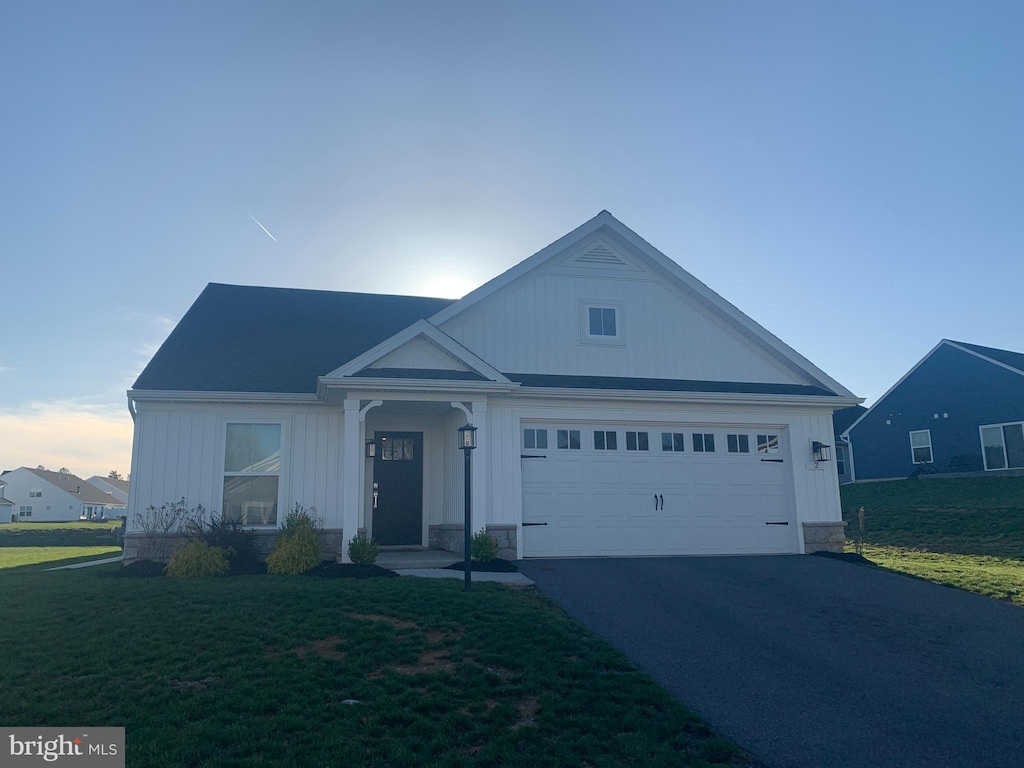 view of front of home with a garage, a front lawn, board and batten siding, and driveway