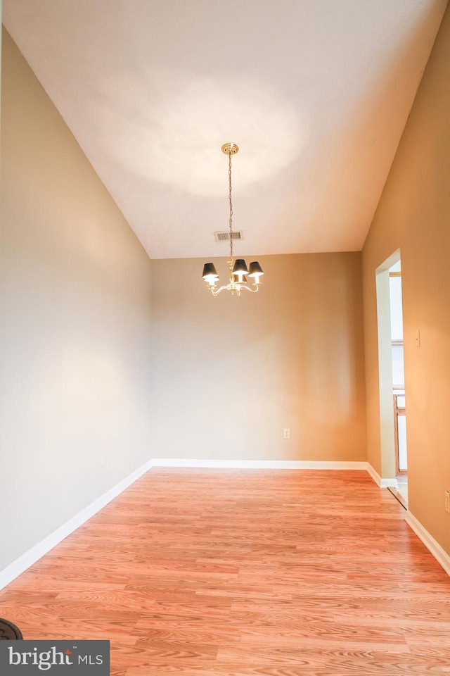 unfurnished room with visible vents, vaulted ceiling, baseboards, light wood finished floors, and a chandelier