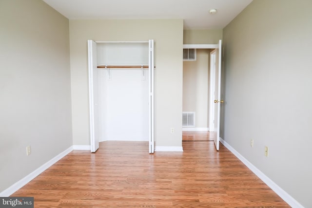unfurnished bedroom with a closet, baseboards, visible vents, and light wood-style floors