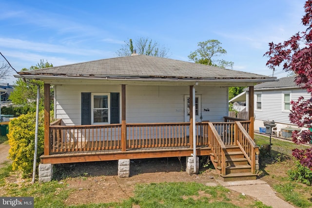 bungalow-style home featuring fence, a shingled roof, and a porch
