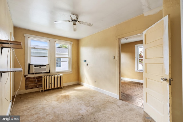 carpeted spare room featuring baseboards, ceiling fan, radiator heating unit, and cooling unit
