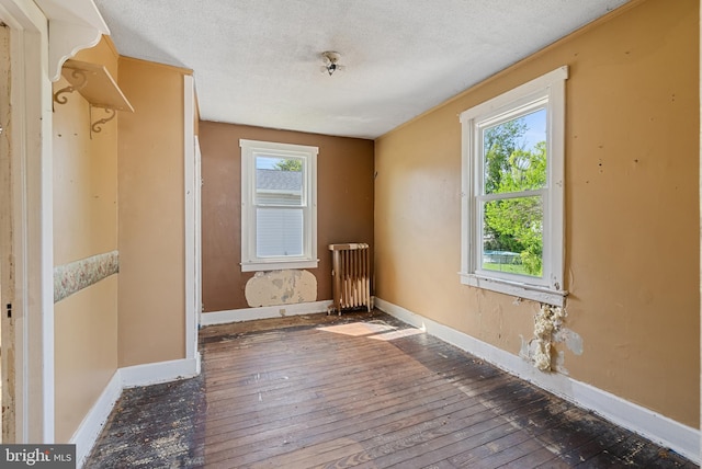 interior space featuring plenty of natural light, radiator, and hardwood / wood-style flooring