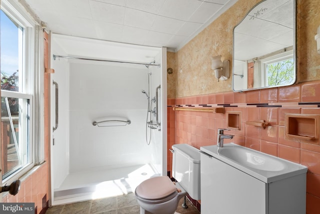 bathroom with vanity, a shower stall, toilet, and tile walls