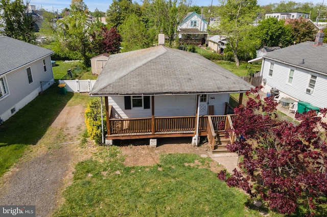 back of house with a residential view, fence, dirt driveway, a gate, and a lawn