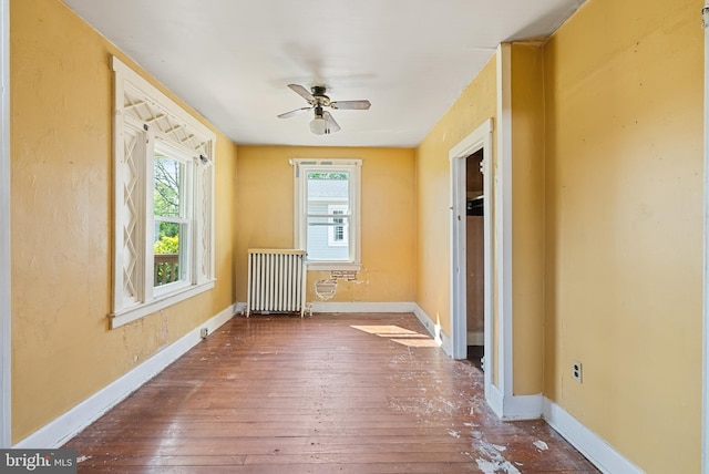 spare room with radiator heating unit, baseboards, ceiling fan, and hardwood / wood-style floors