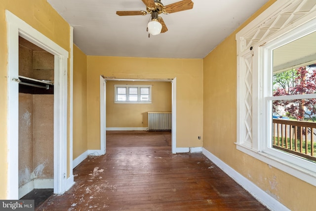 hallway with wood-type flooring, baseboards, and radiator heating unit