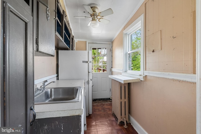 washroom with ceiling fan, a sink, radiator heating unit, baseboards, and ornamental molding