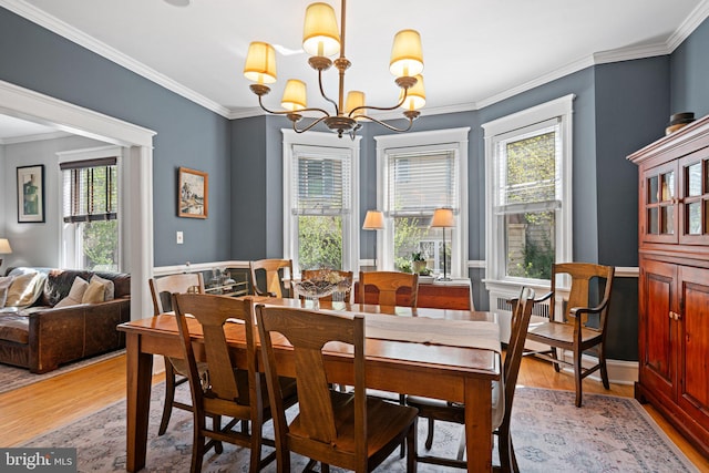 dining space with crown molding, light wood finished floors, and a chandelier