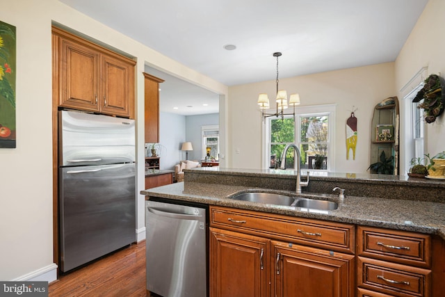 kitchen with brown cabinetry, a sink, dark wood-style floors, and stainless steel appliances