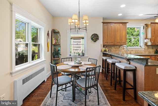 dining area with dark wood-style flooring, baseboards, a chandelier, radiator, and recessed lighting