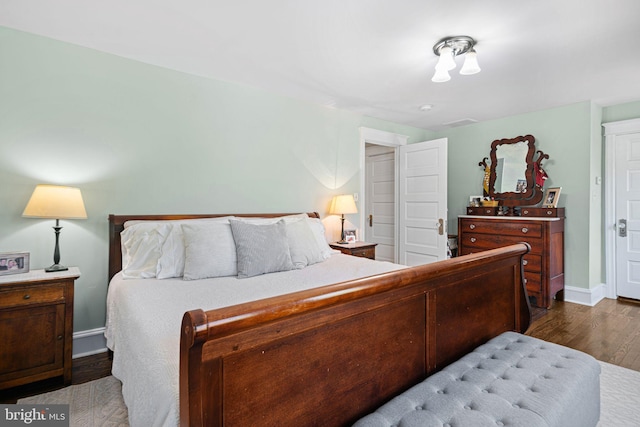 bedroom with baseboards, wood finished floors, and visible vents