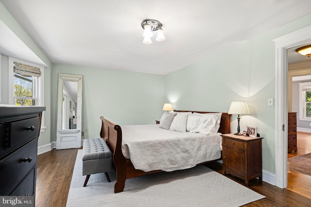 bedroom with baseboards and dark wood-type flooring