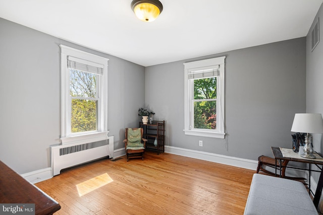 living area with baseboards, visible vents, radiator heating unit, and wood finished floors
