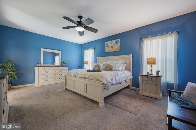 carpeted bedroom featuring baseboards, ceiling fan, and multiple windows
