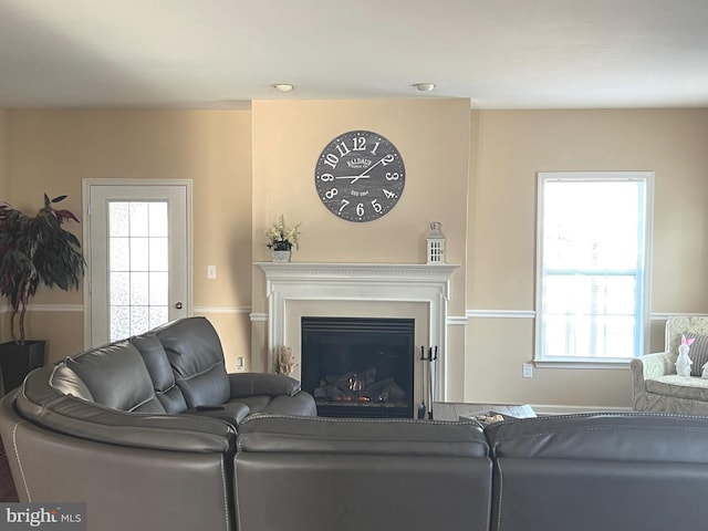 living room featuring a healthy amount of sunlight and a glass covered fireplace