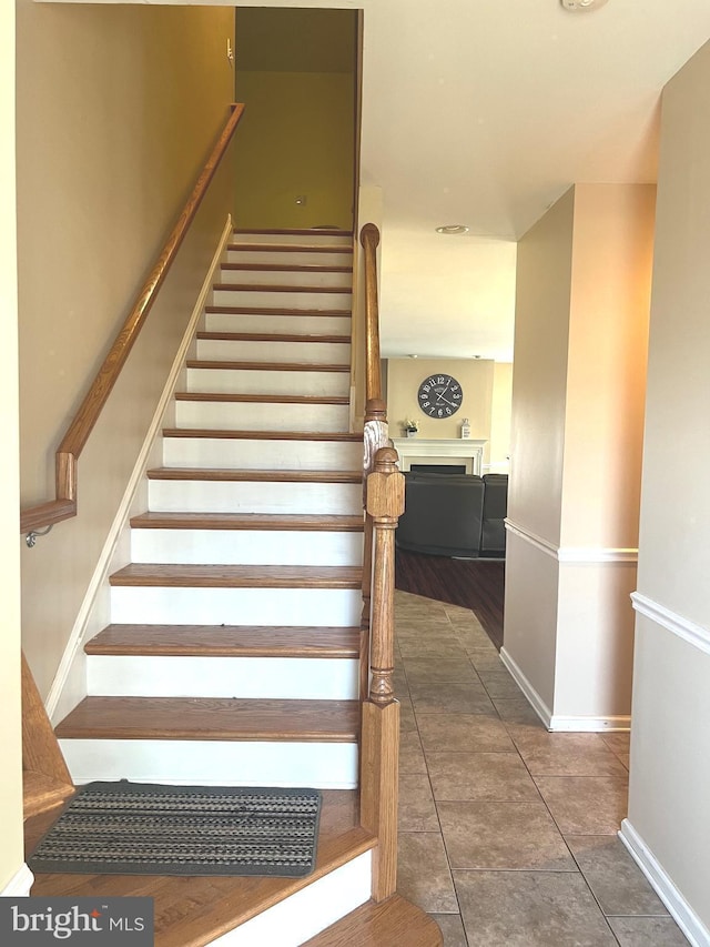 stairs with baseboards, tile patterned floors, and a fireplace