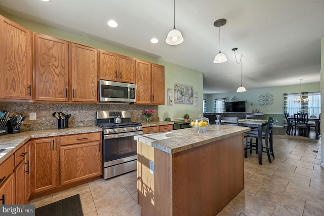 kitchen with a center island, hanging light fixtures, tasteful backsplash, light countertops, and stainless steel appliances