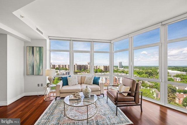 sunroom featuring baseboards, wood finished floors, a wealth of natural light, and a wall of windows