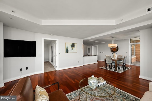 living room featuring baseboards, wood finished floors, and a tray ceiling